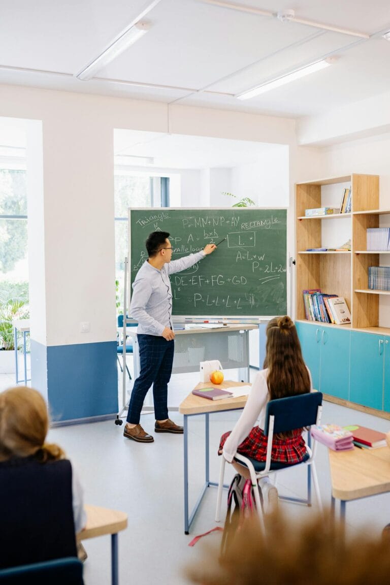 Instructor teaching students in a bright classroom, emphasizing interactive learning.